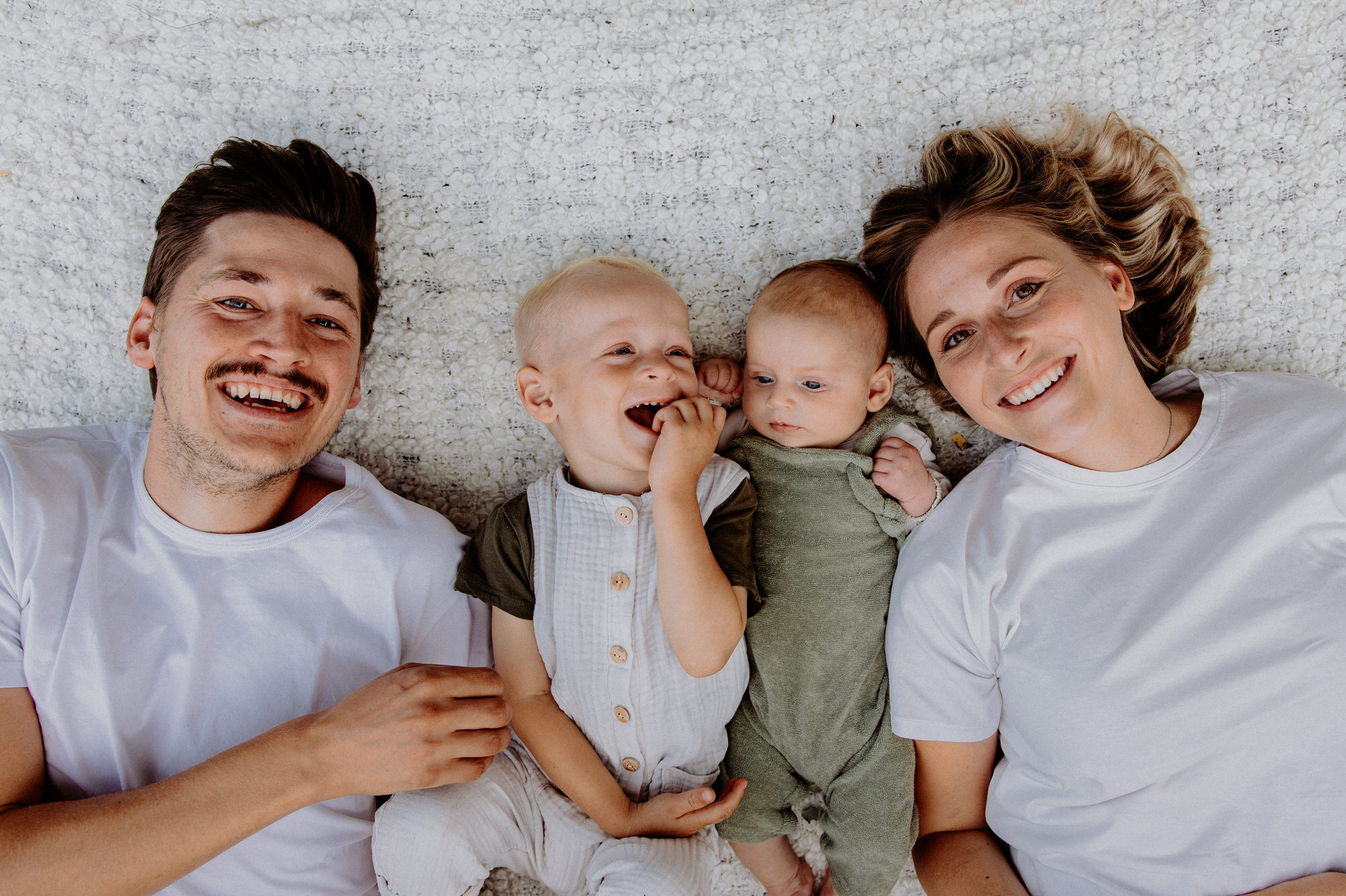 Eltern mit zwei Kindern auf einer Decke im Gras liegend